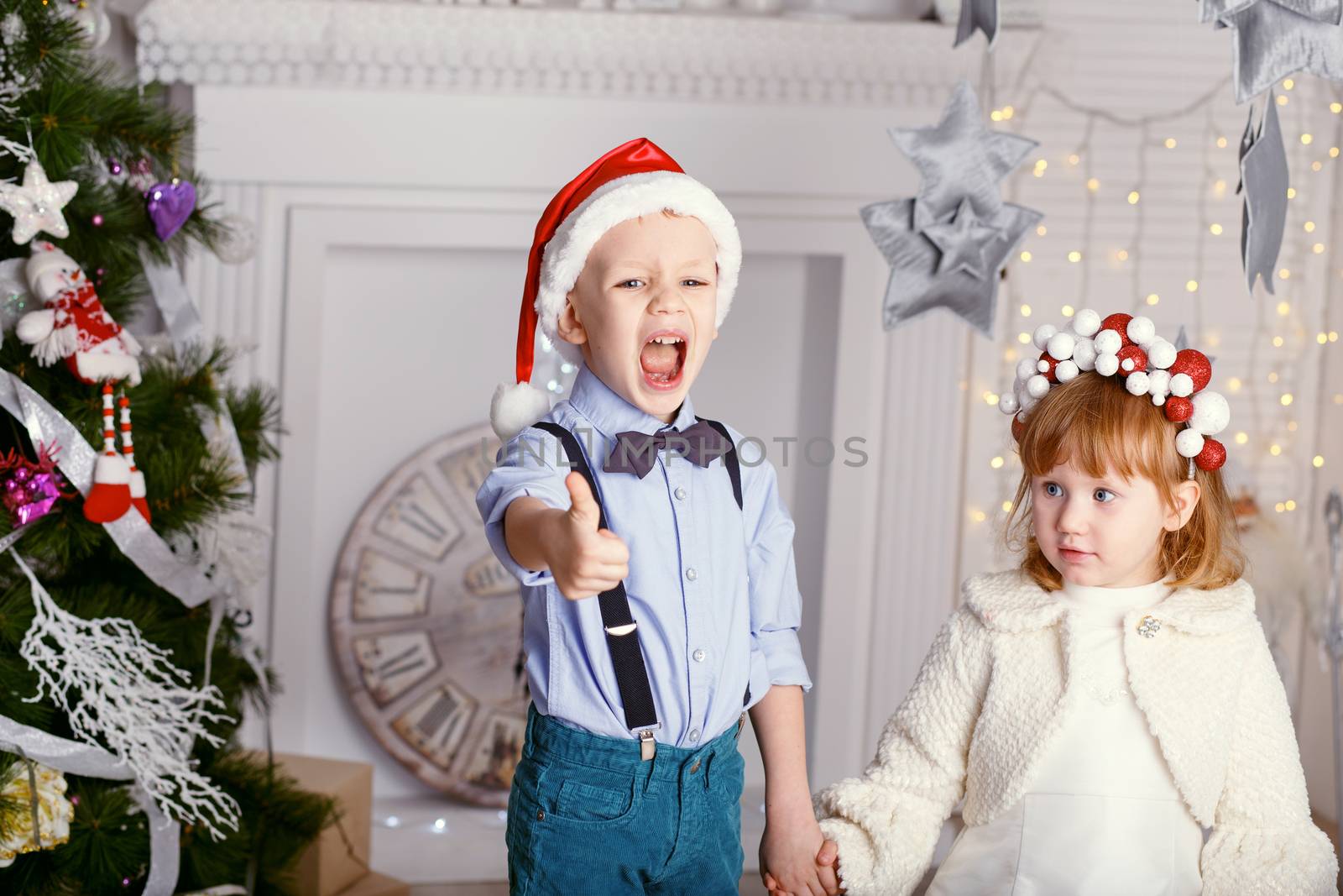 Two little children having fun near the Christmas tree. New year celebration. Happy kids and family.