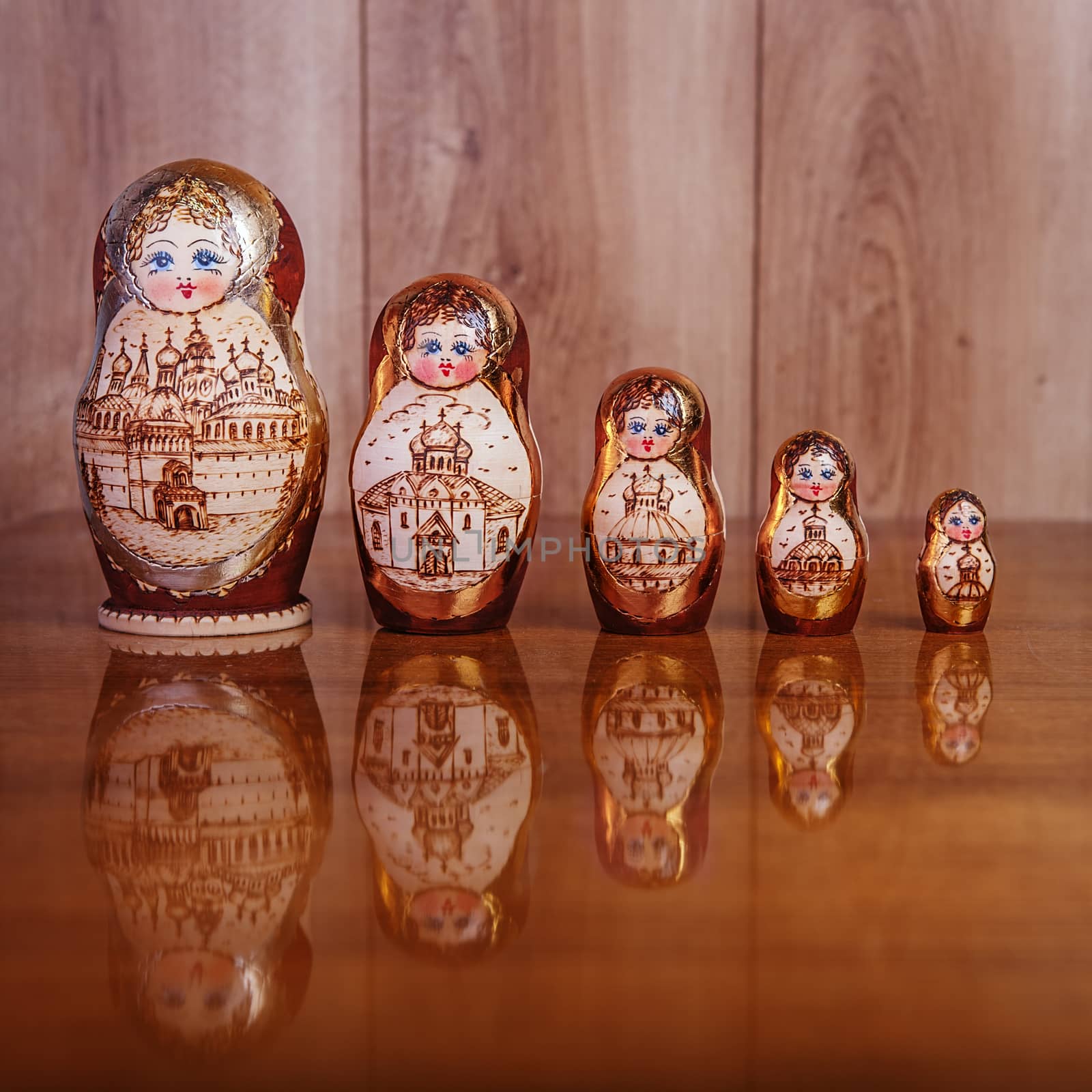 Five dolls on a brown wooden table and a texture on a wooden background
