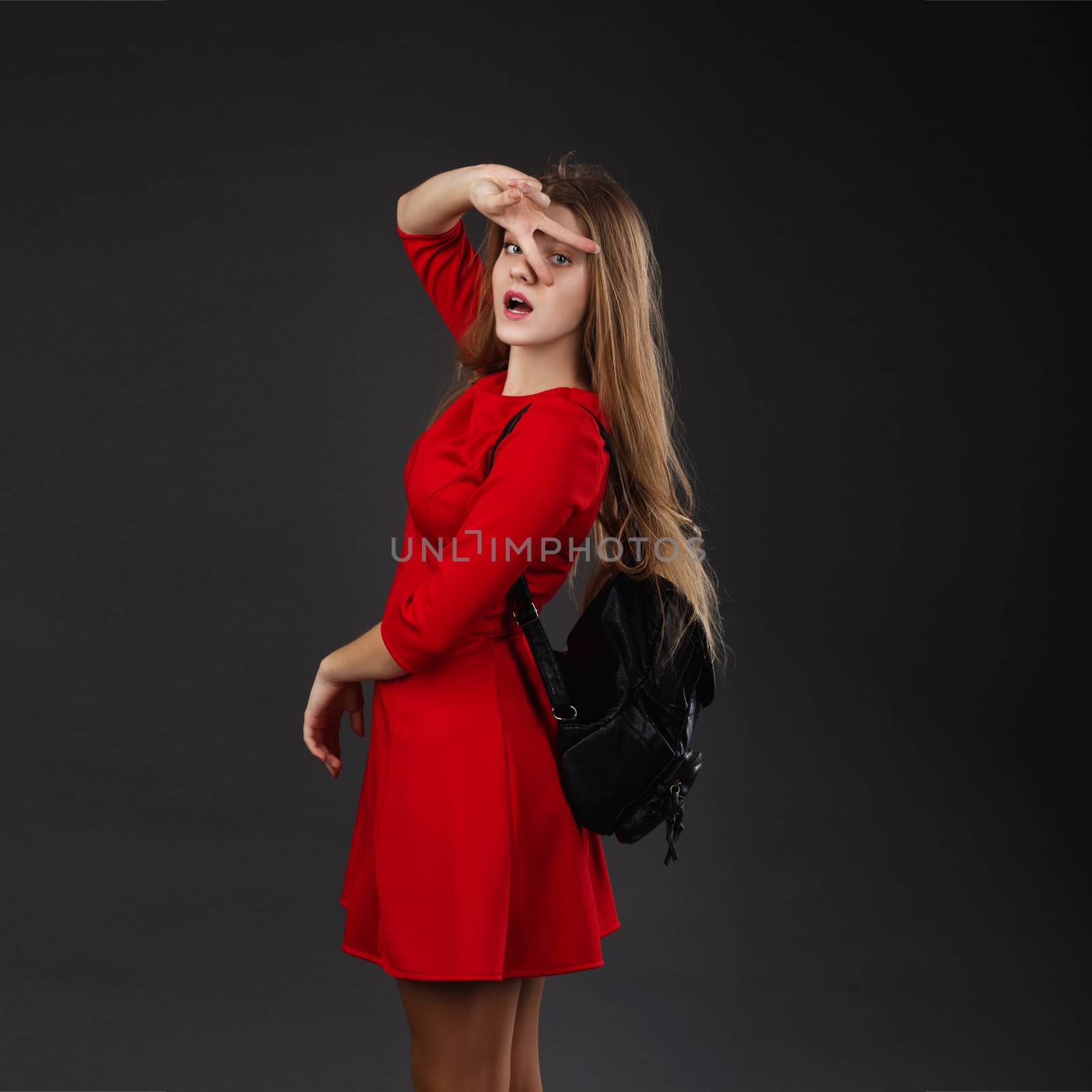 Portrait of a girl in a red dress with a black leather backpack by natazhekova