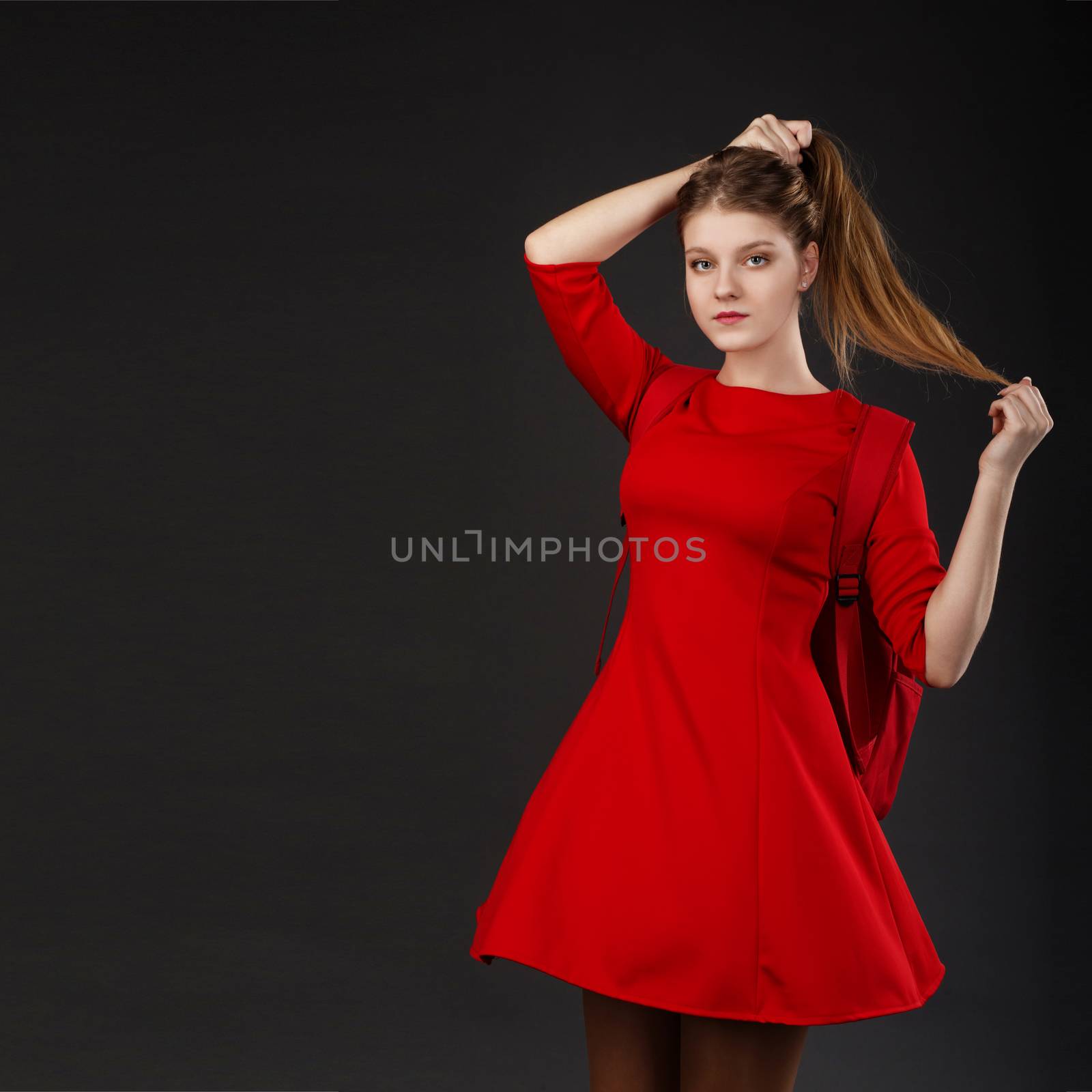Portrait of a beautiful girl with long hair in a red dress