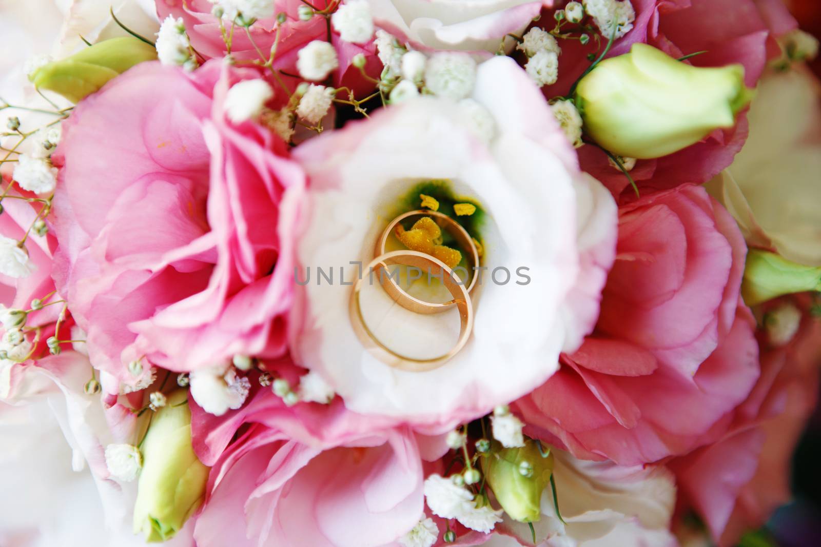 Great bridal bouquet of roses, peonies and dried flowers. Gold wedding rings on a bouquet