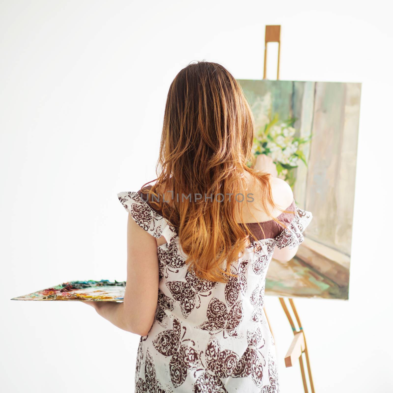 Woman Painting on a Canvas against white background. Back view.