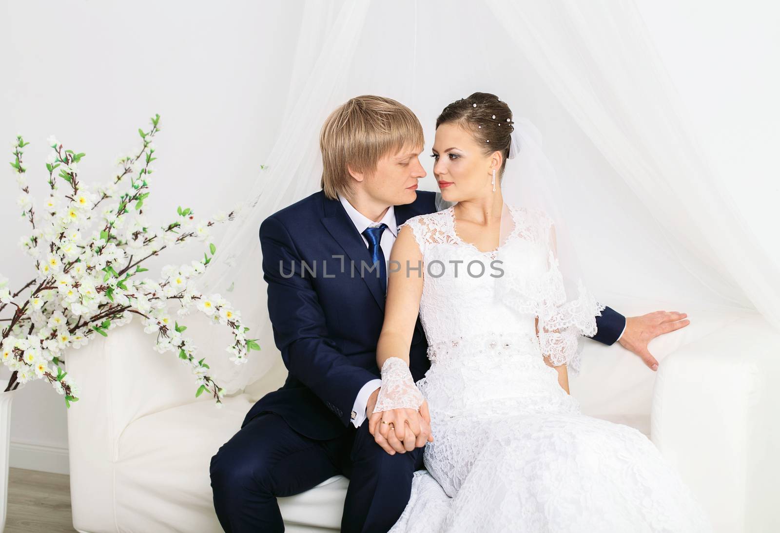 Romantic sensual newlyweds posing on luxury white sofa