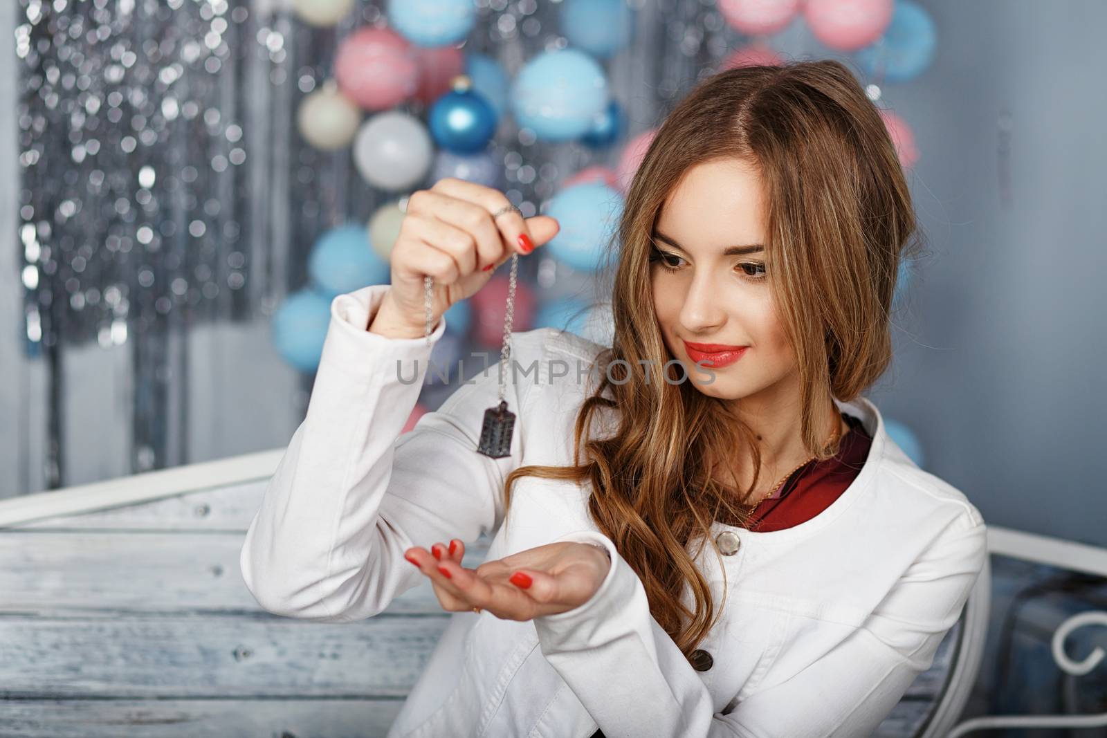 Portrait of a beautiful girl in white jacket with accessory holding in the studio with Christmas decorations