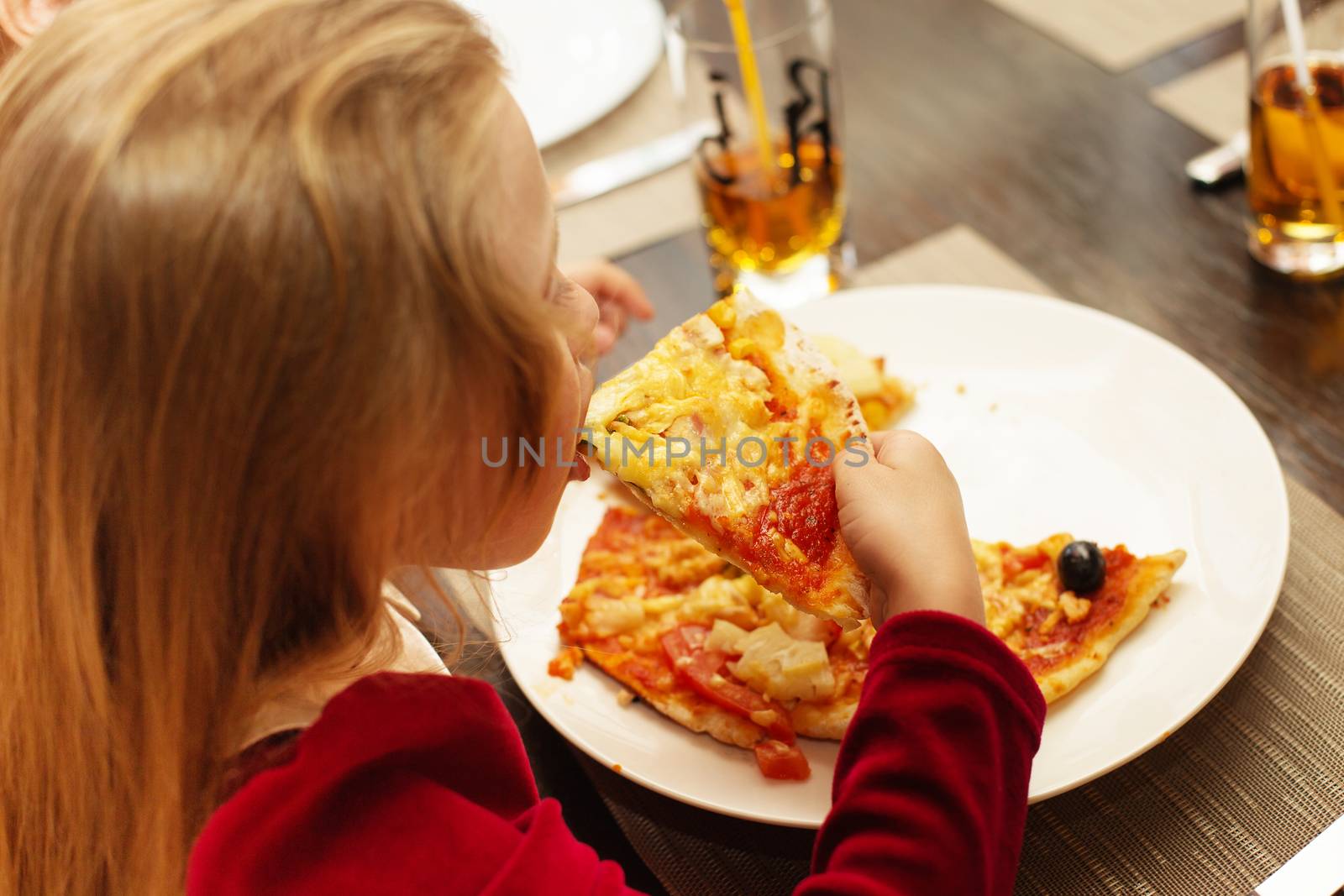 Children eat Italian pizza in the cafe. Adorable little girl eating pizza at a restaurant