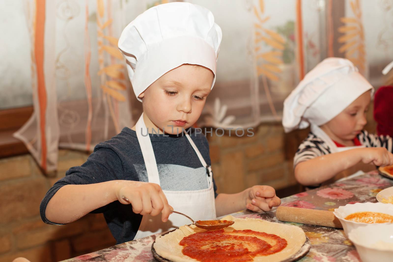 Little cook. Children make pizza. Master class for children on cooking Italian pizza. Young children learn to cook a pizza. Kids preparing homemade pizza