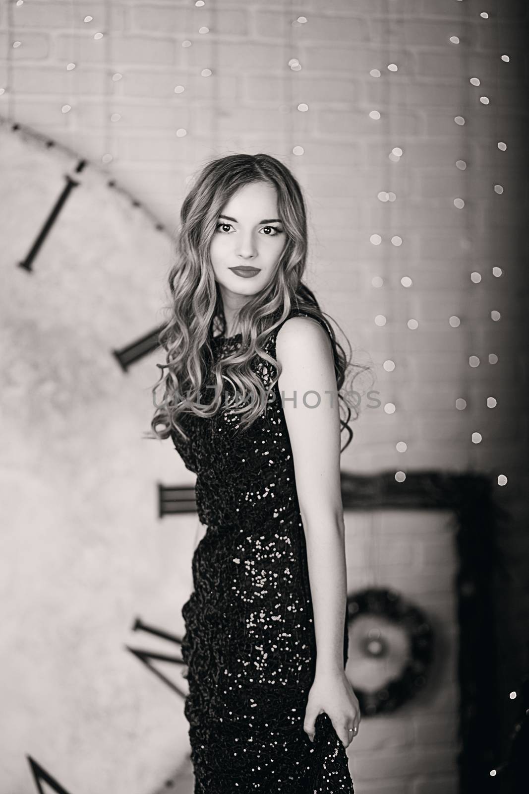 Portrait of a beautiful long-haired young girl in black Evening Dress in interior with Christmas decorations. Black and white photography