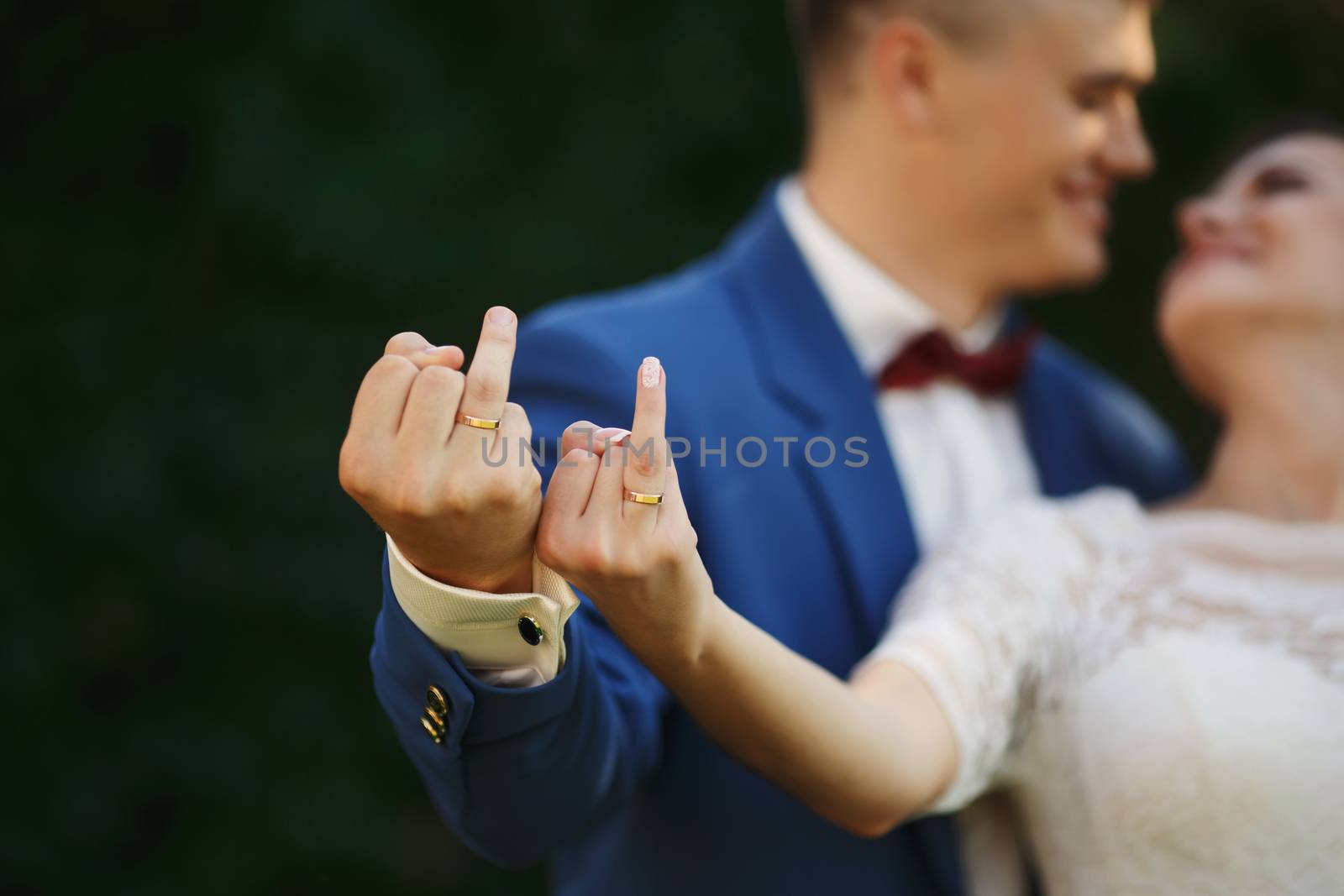 Hands of bride and groom in wedding rings. Couple playfully show their rings