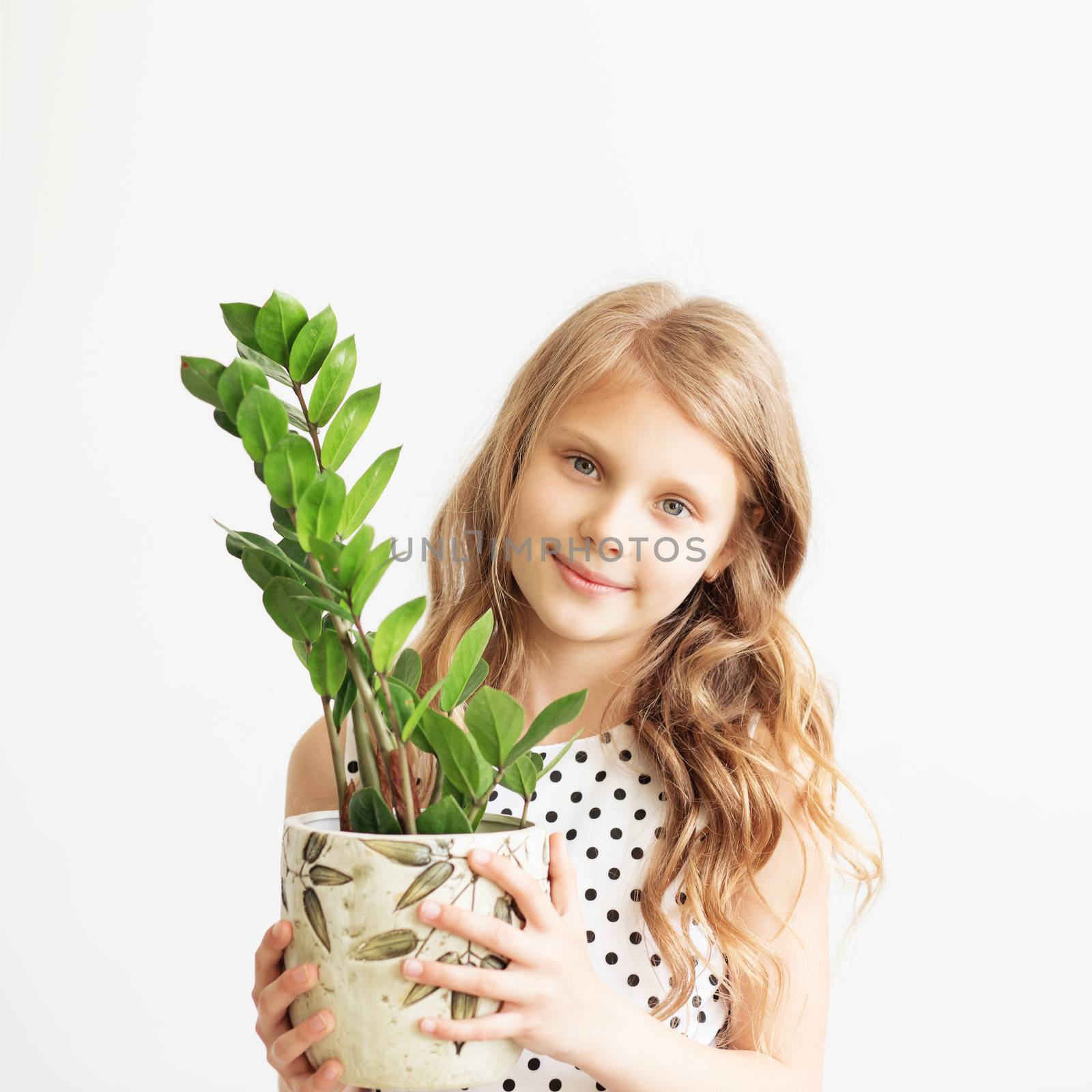 Portrait of a lovely little girl with green houseplant by natazhekova