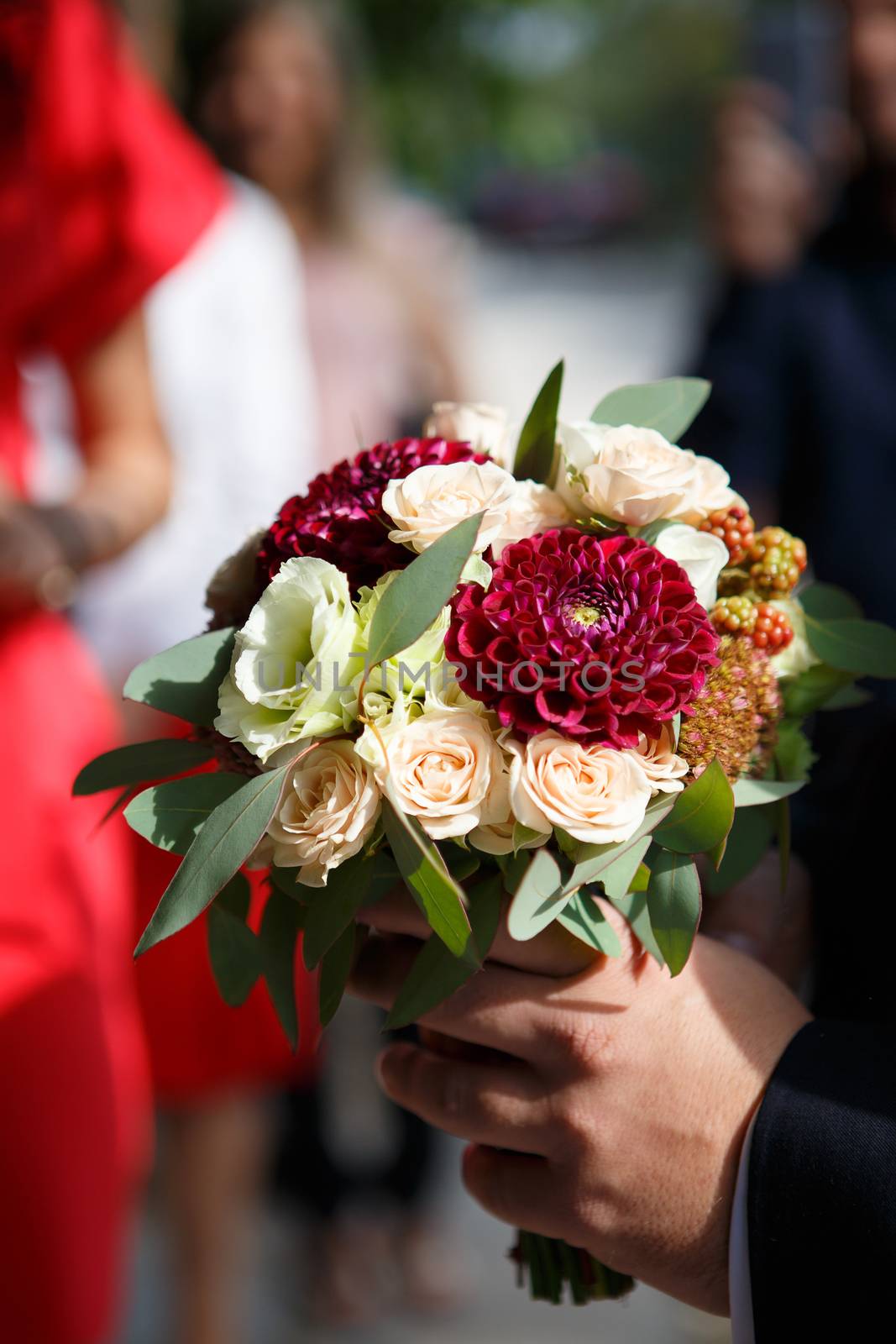 The groom brings a bouquet for the bride. Groom with bridal bouquet of roses, berries and dahlias
