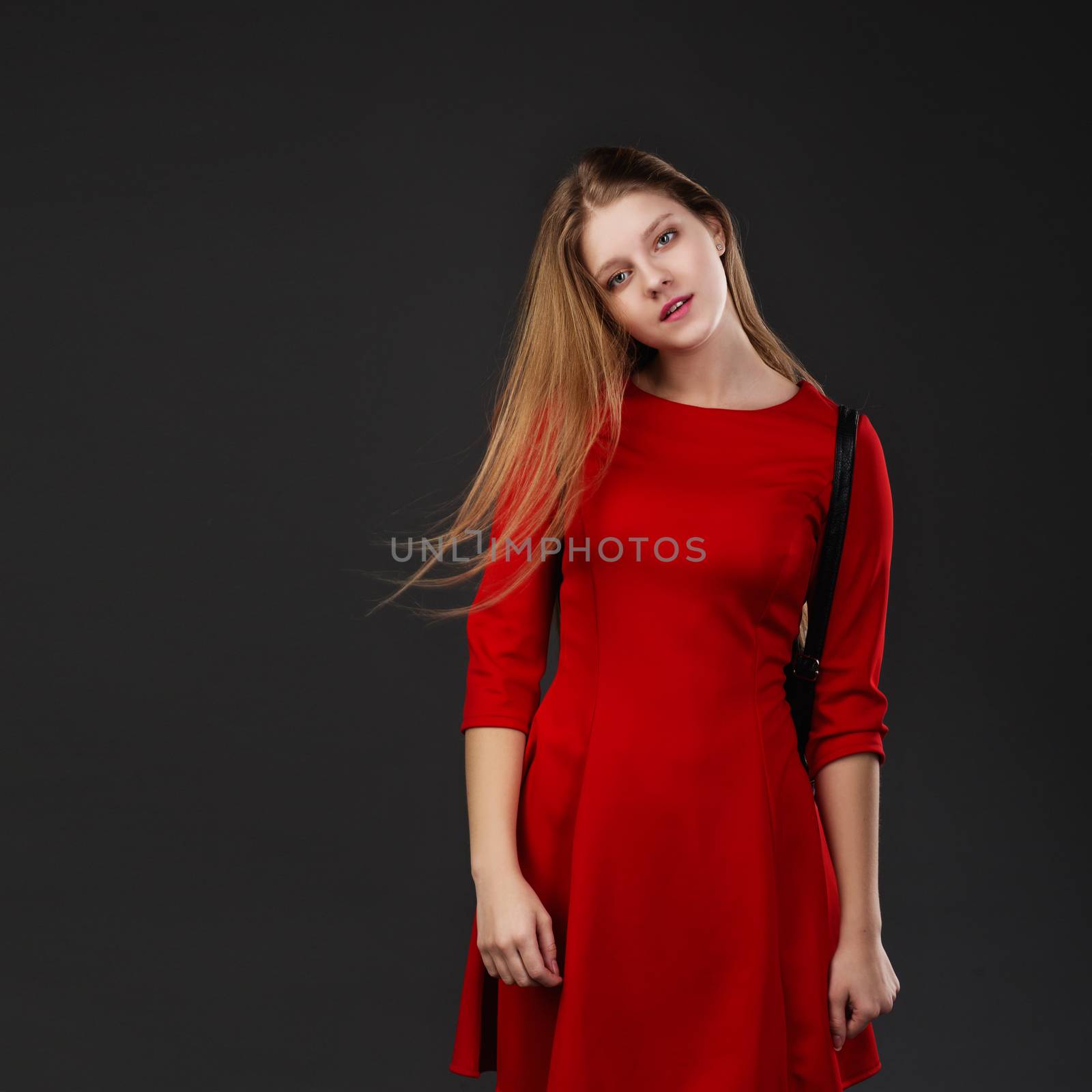 Beautiful girl with hair motion freeze over gray background. Blonde woman with her long hair blowing looking at camera. The concept of hair care products. Healthy long shiny hair