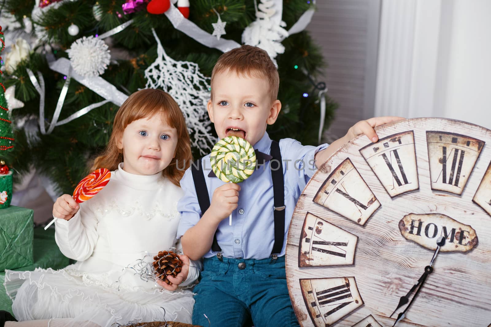 Little children eating a lollipops. Portrait of two funny little kids with delicious candies in the hands. Happy children and family In anticipation of new year and Christmas.