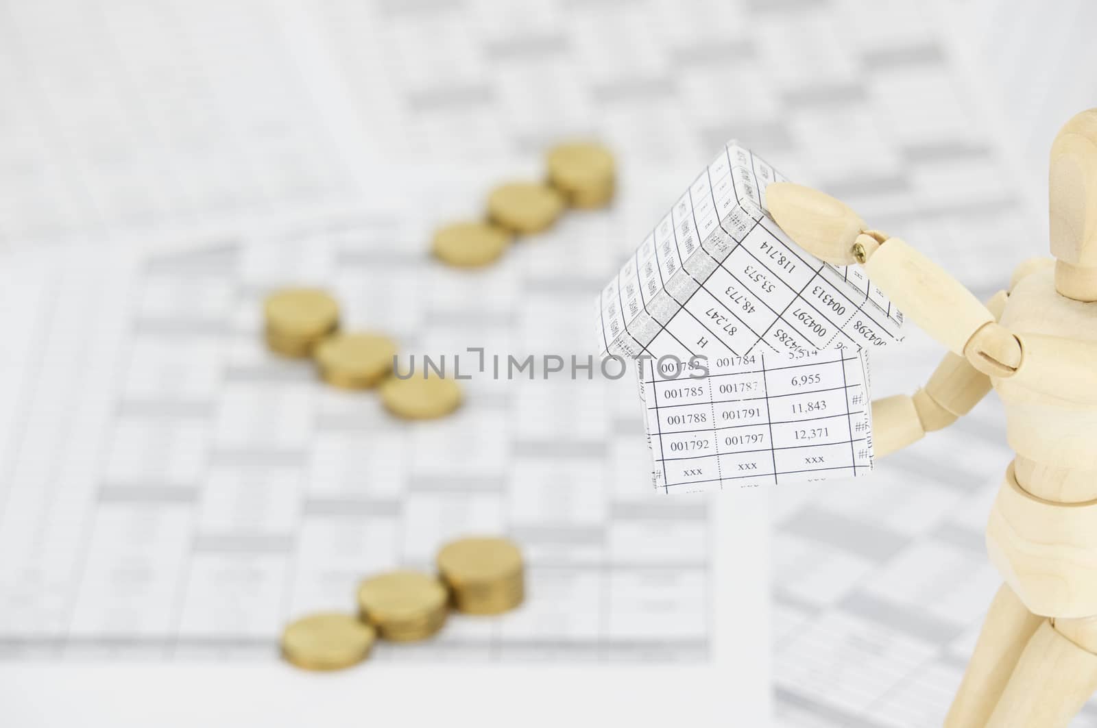 Wooden dummy holding house have blur gold coins as background by eaglesky