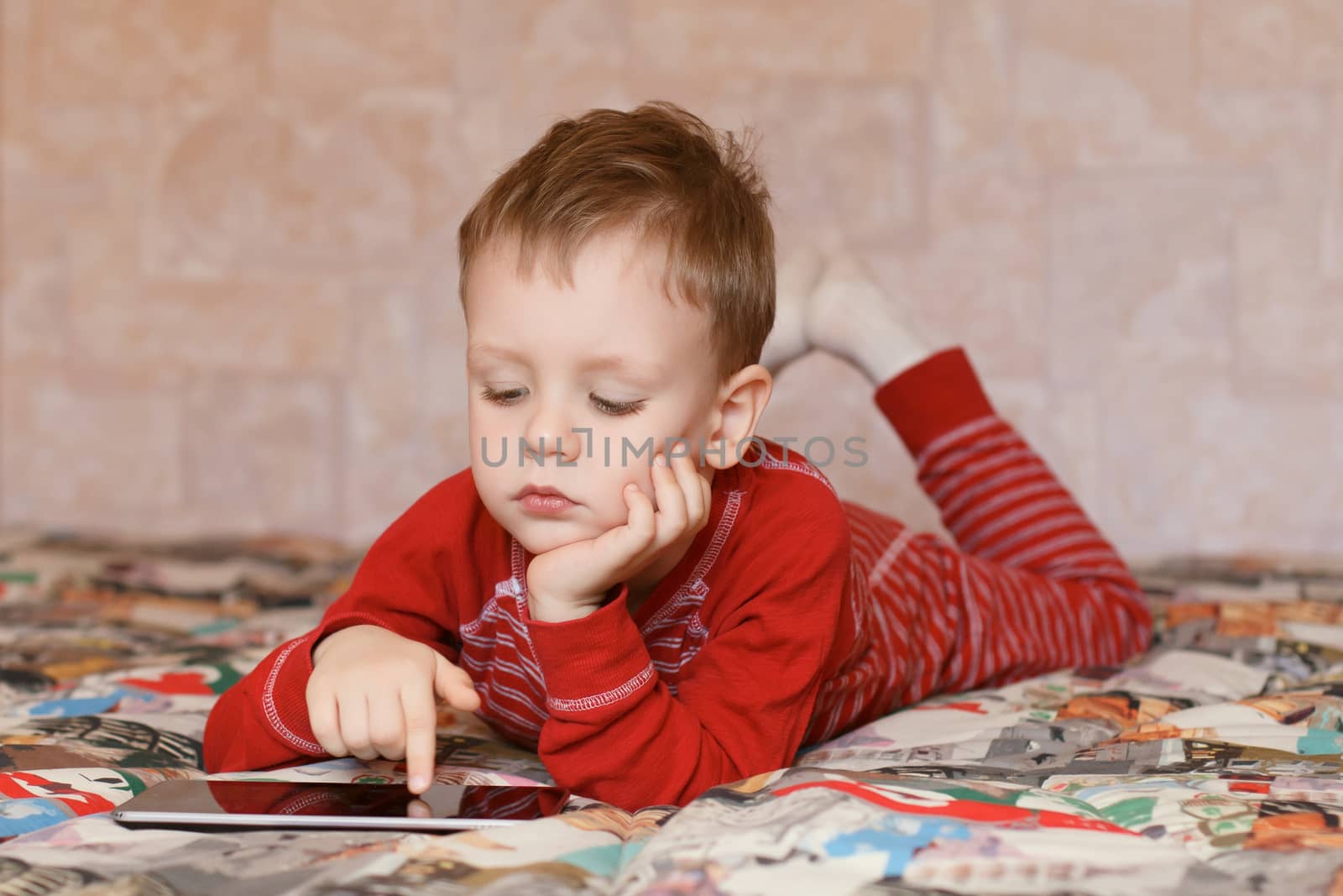 Little boy playing on the tablet computer at home