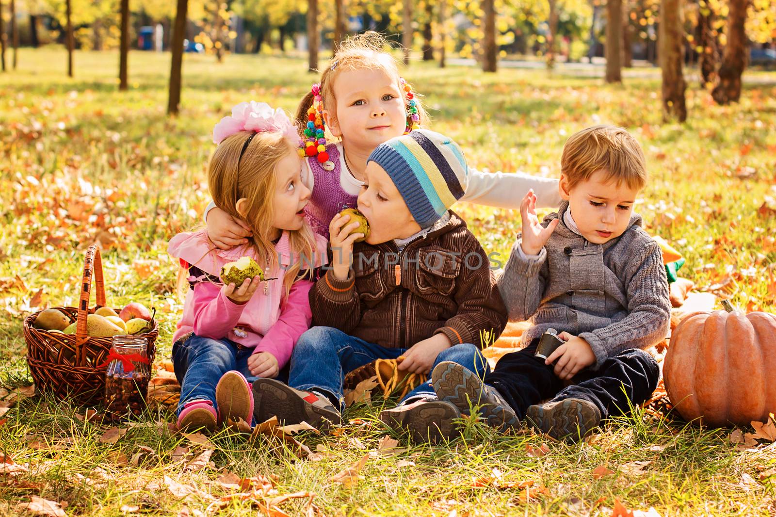 Four happy children playing in autumn park with fruits