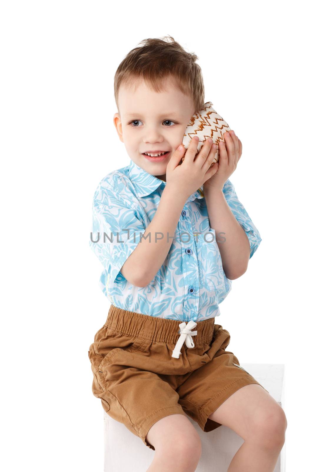Little handsome boy listens to the sea through the shell