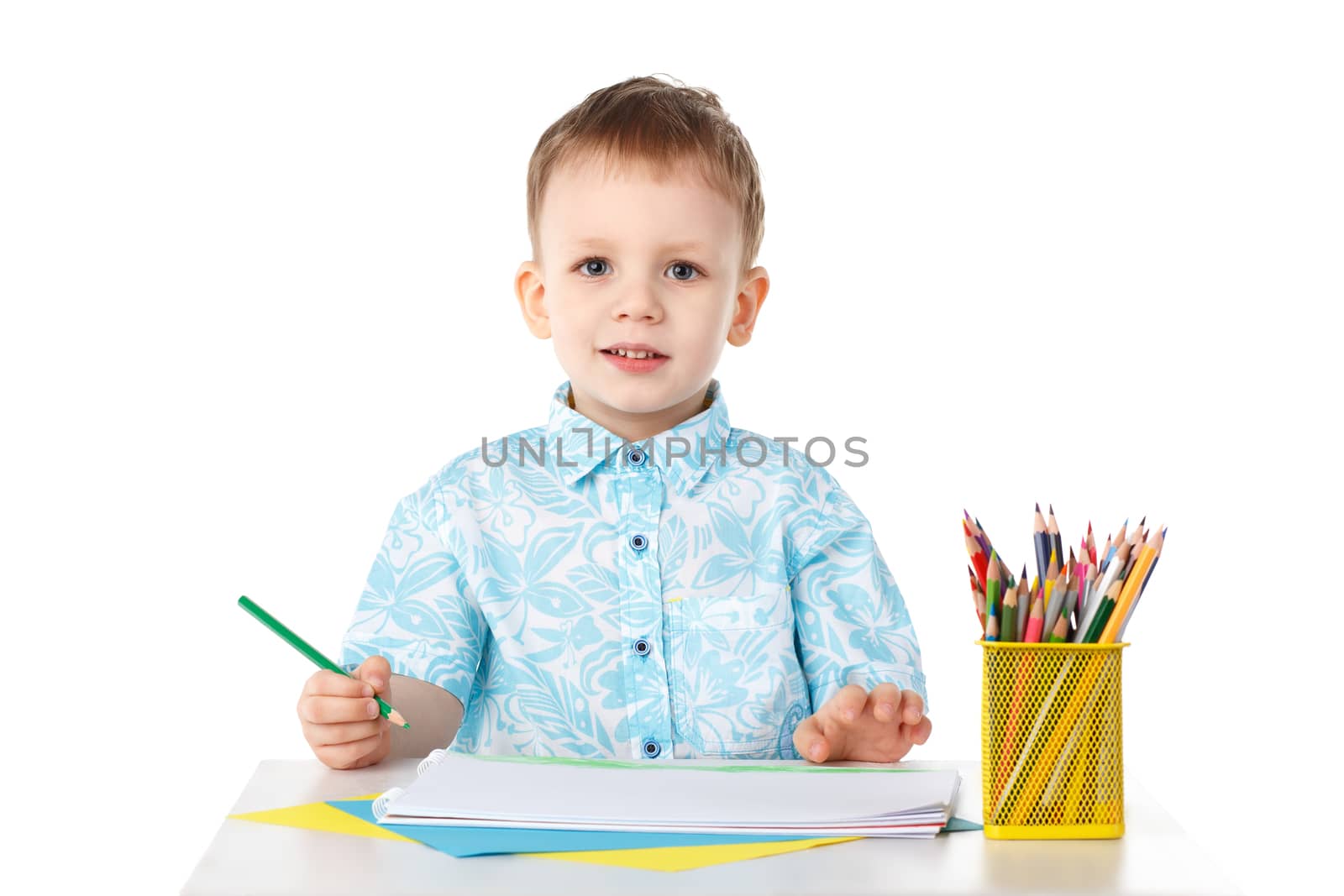 Smiling little boy draws with crayons isolated on white background