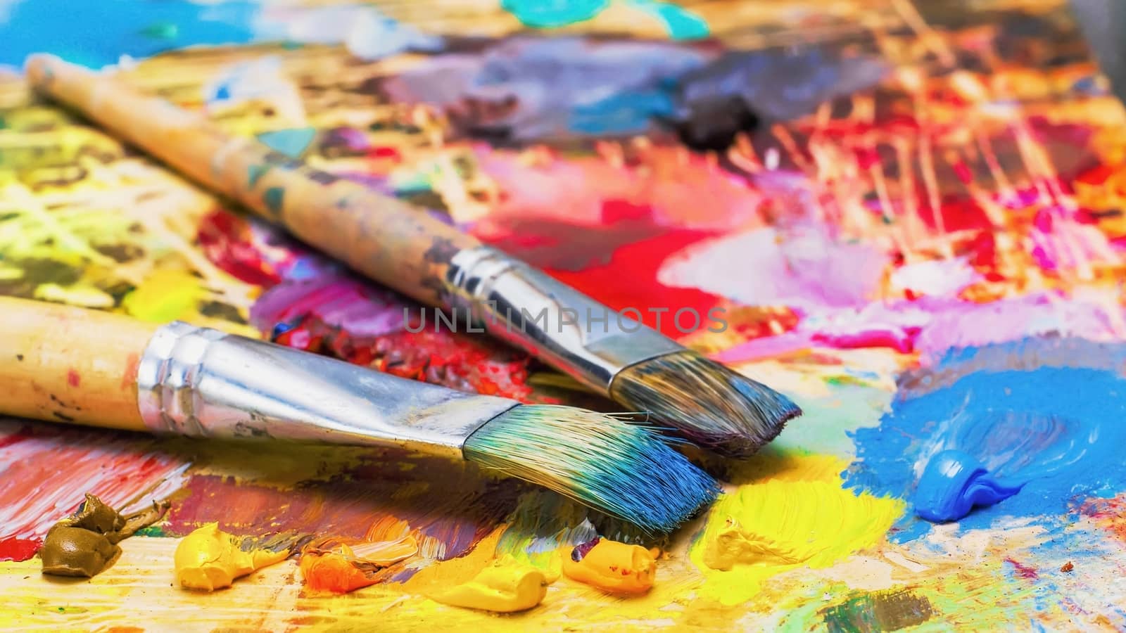 Used brushes on an artist's palette of colorful oil paint by KoliadzynskaIryna