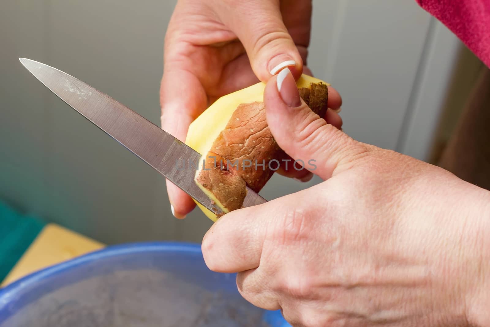 close-up of hands peeling potatoes, cleaning raw fresh potatoes, cooking in the kitchen