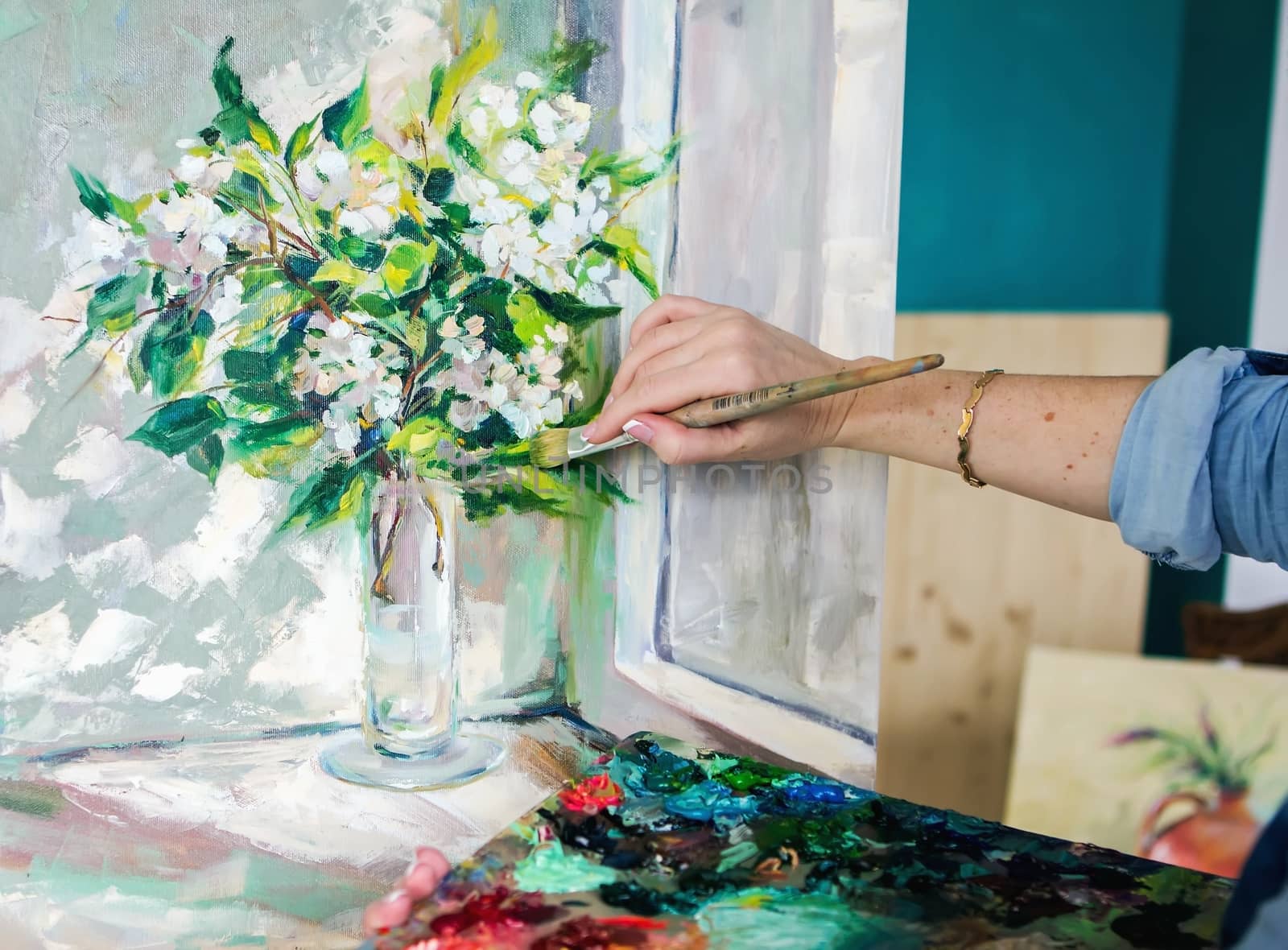 Brush and oil paints on a palette, paint a picture of the artist's hands, texture mix paint in different colors. Artist holding a palette with paint, brushes and palette knife