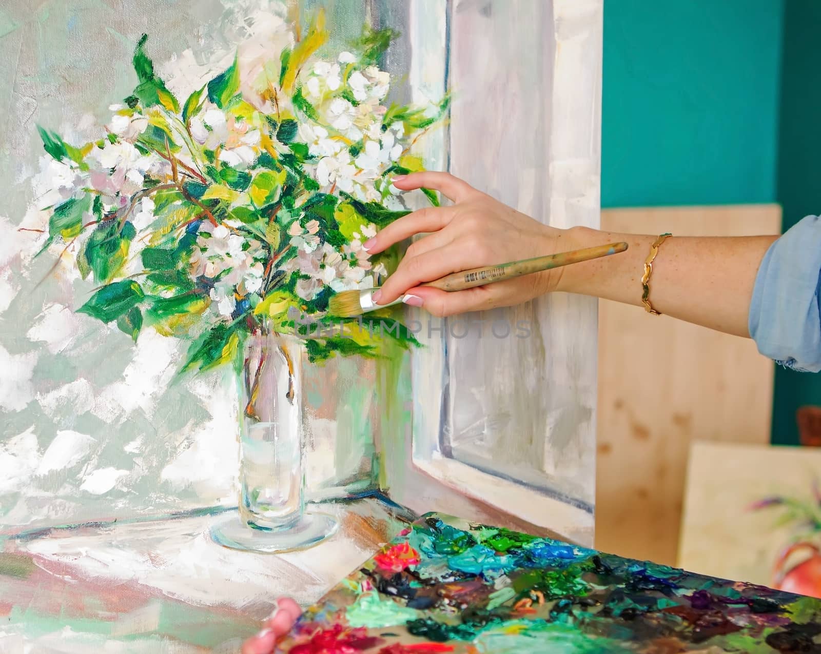 Brush and oil paints on a palette, paint a picture of the artist's hands, texture mix paint in different colors. Artist holding a palette with paint, brushes and palette knife