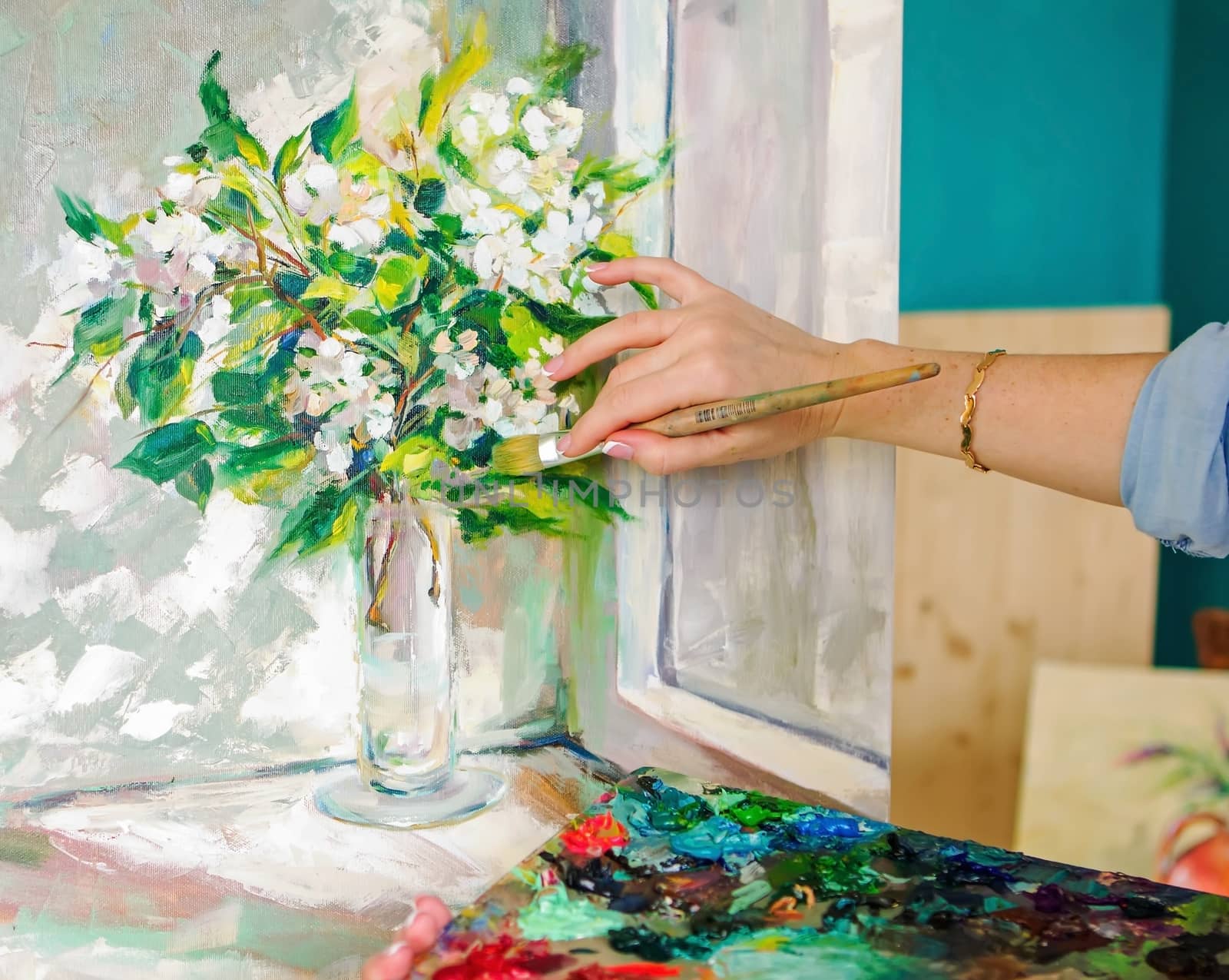 Brush and oil paints on a palette, paint a picture of the artist's hands, texture mix paint in different colors. Artist holding a palette with paint, brushes and palette knife