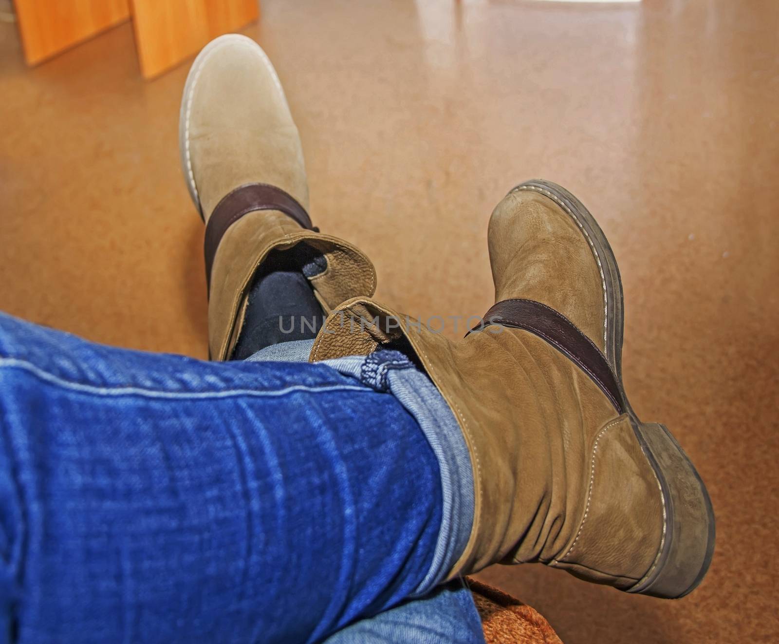 female legs in brown boots, women's shoes, sitting on the couch