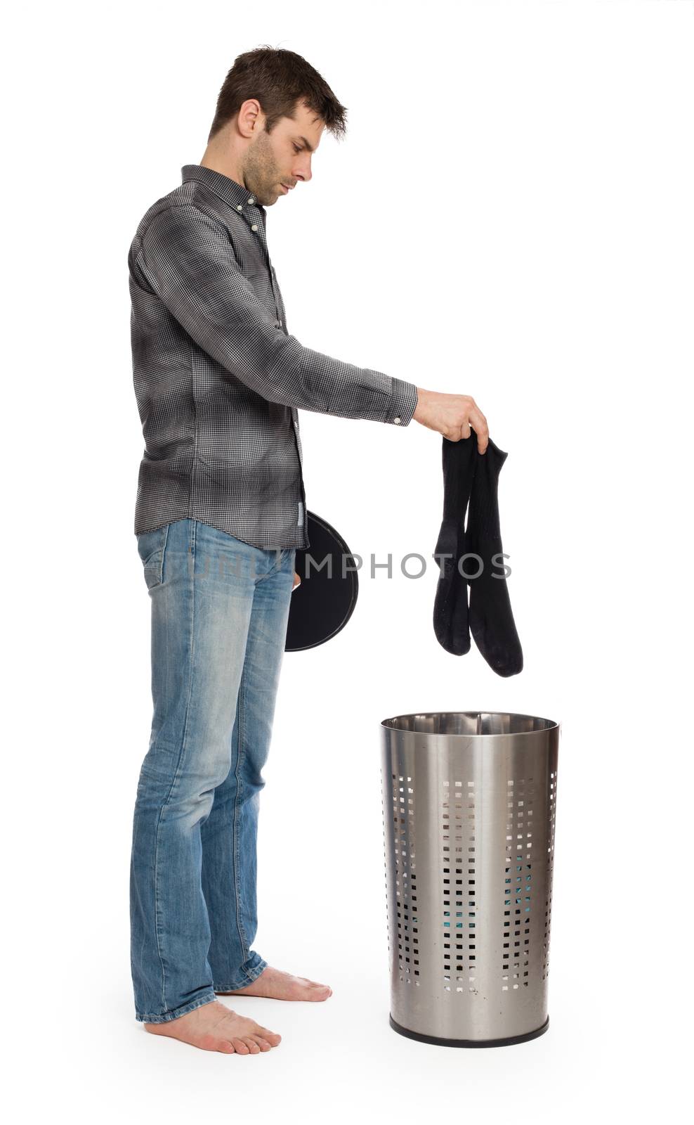 Young man putting a dirty socks in a laundry basket, isolated