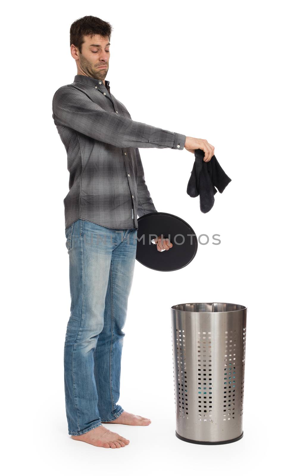 Young man putting a dirty socks in a laundry basket by michaklootwijk