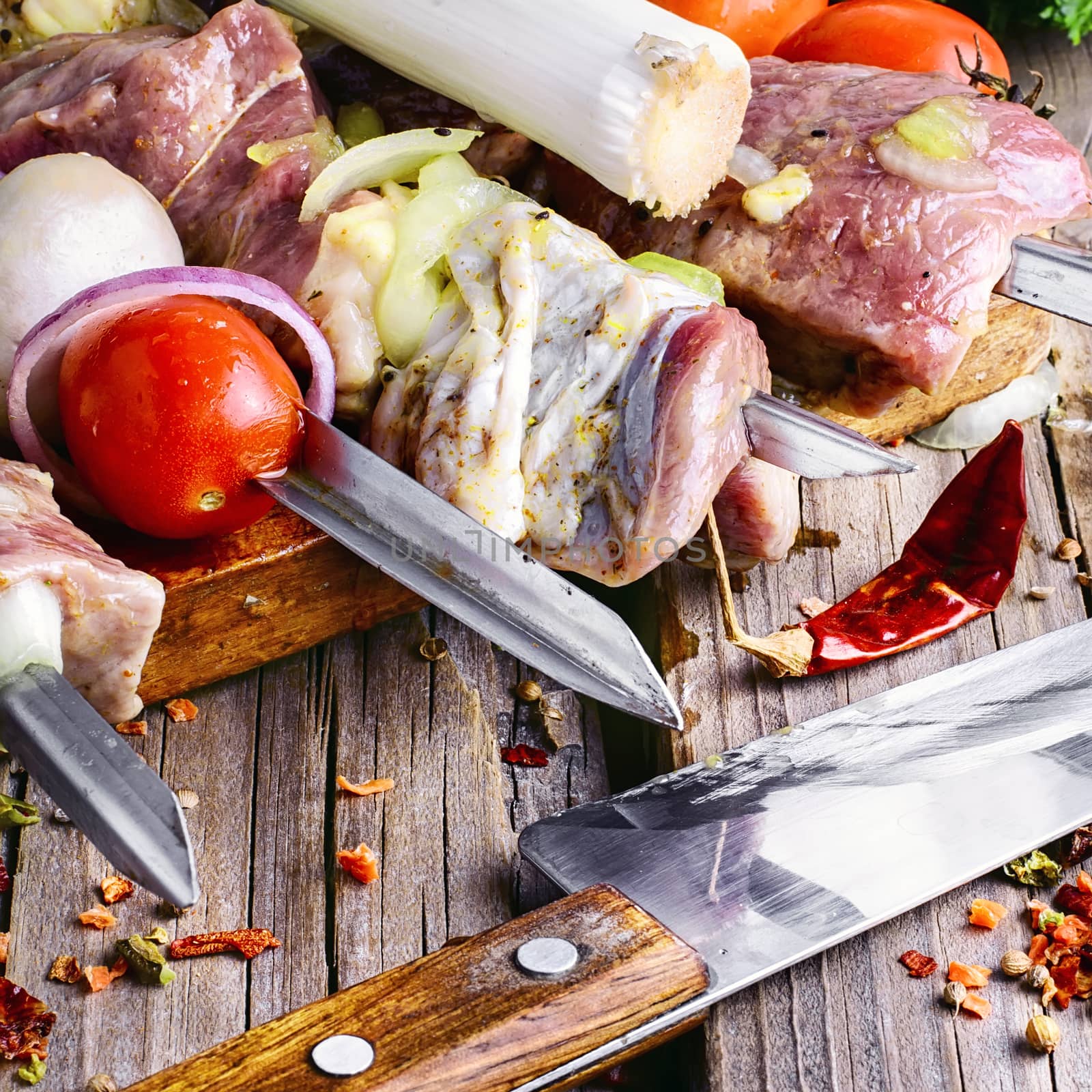 Juicy chunks of raw pork threaded on skewers with onions and tomatoes