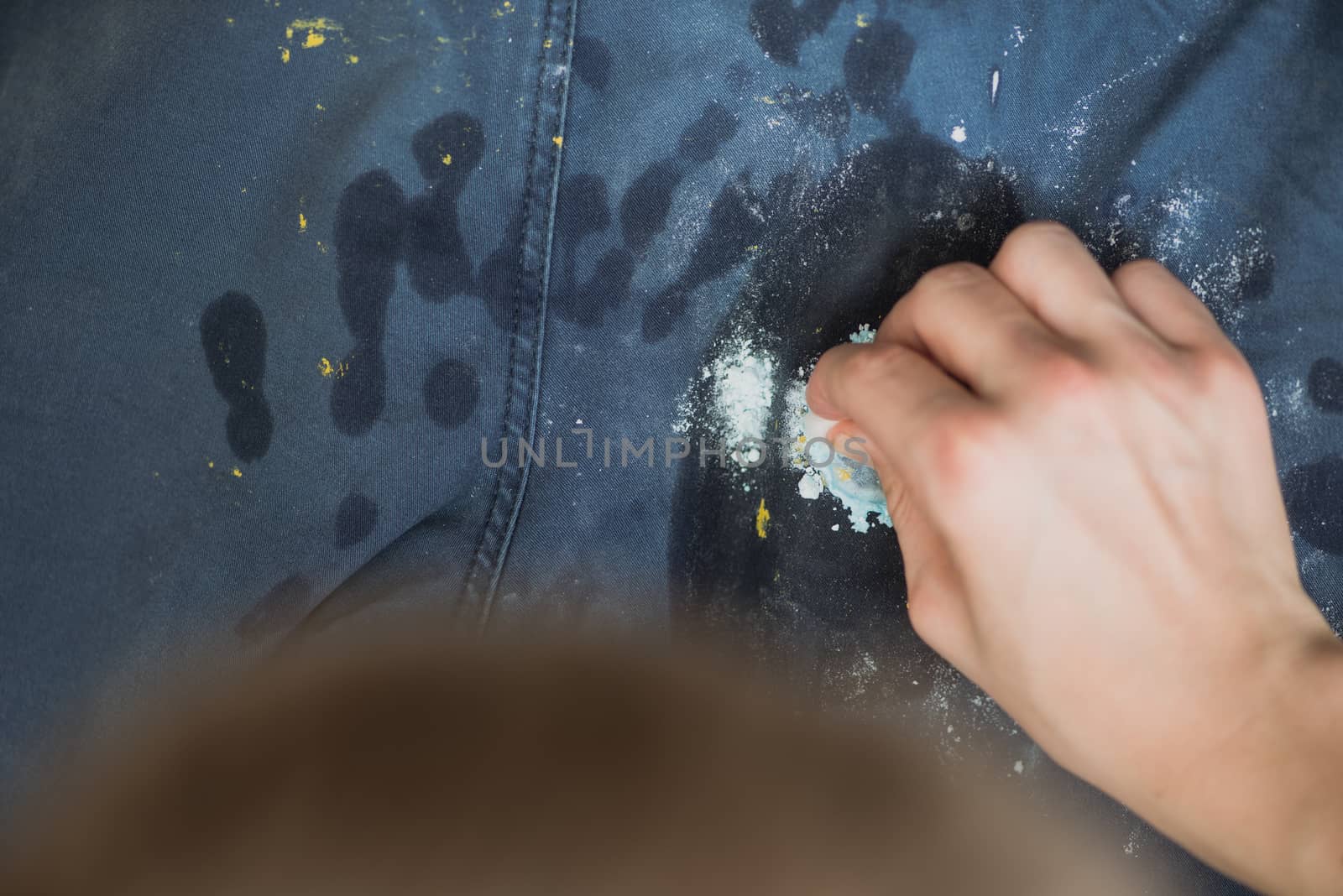 boy wipes the paint on his pants. Blue Jeans and sneakers stained with yellow paint. Top view. by skrotov