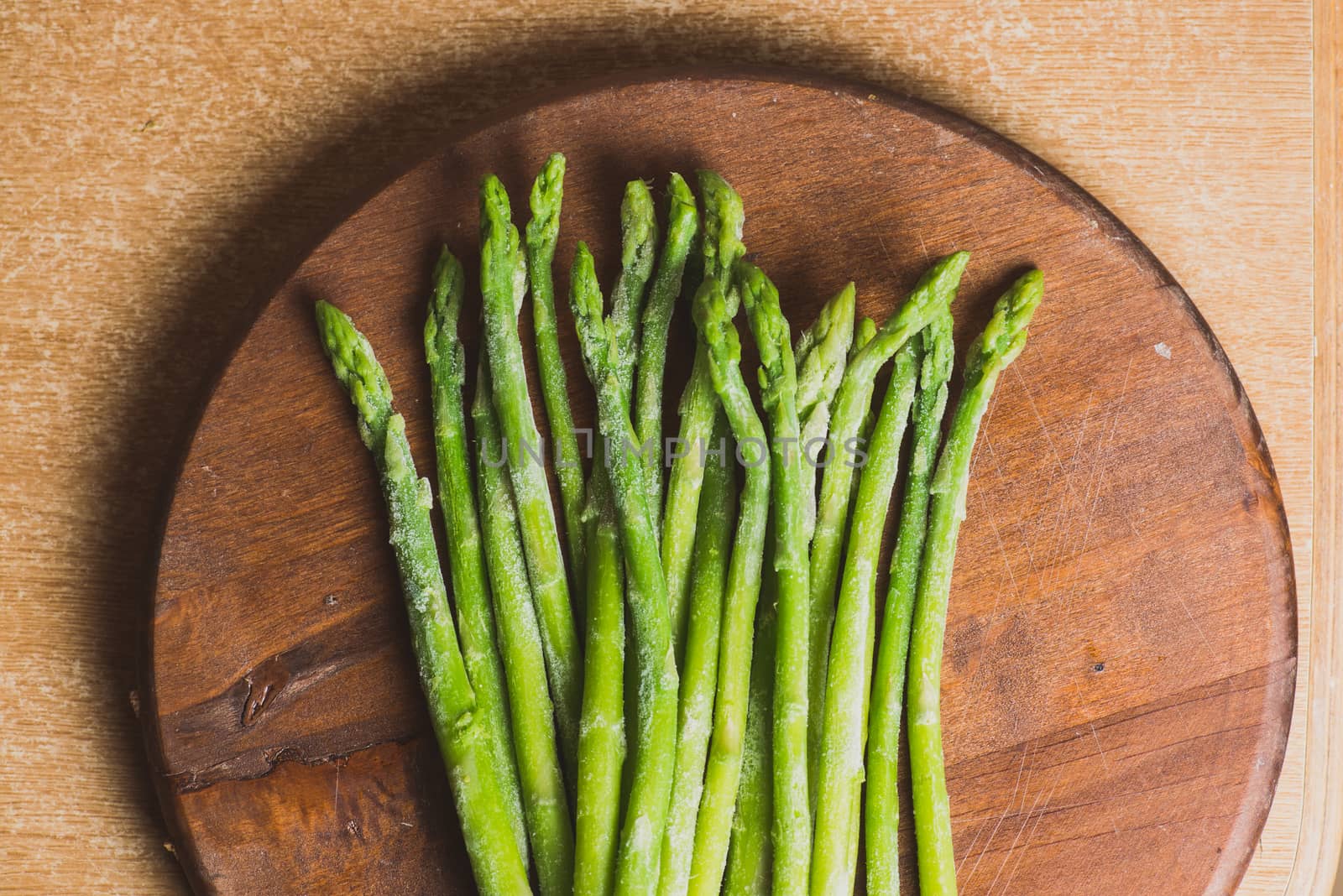 Frozen sticks of asparagus on rustic wood background. horizontal view. by skrotov