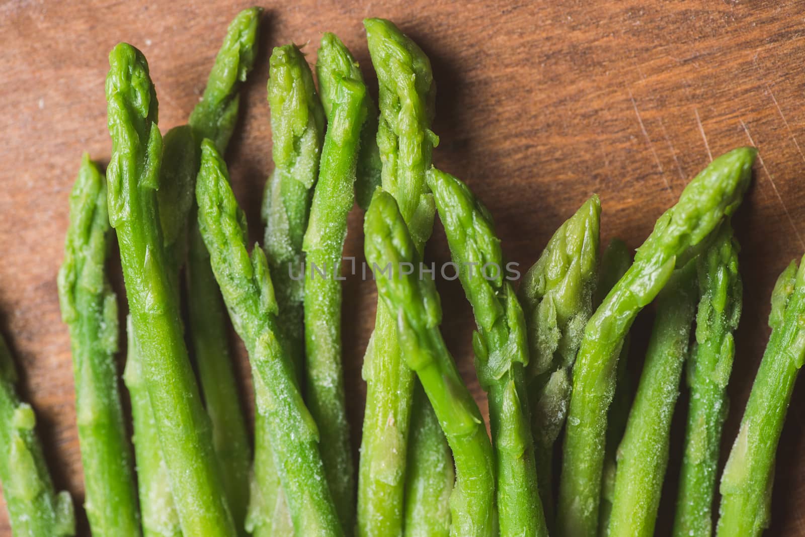 Frozen sticks of asparagus on rustic wood background. horizontal view. by skrotov