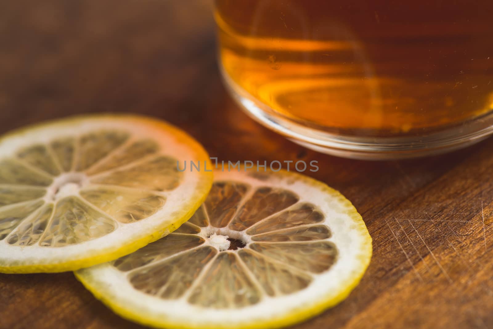 perspective view of black tea with lemon in cup and on wooden plank table.