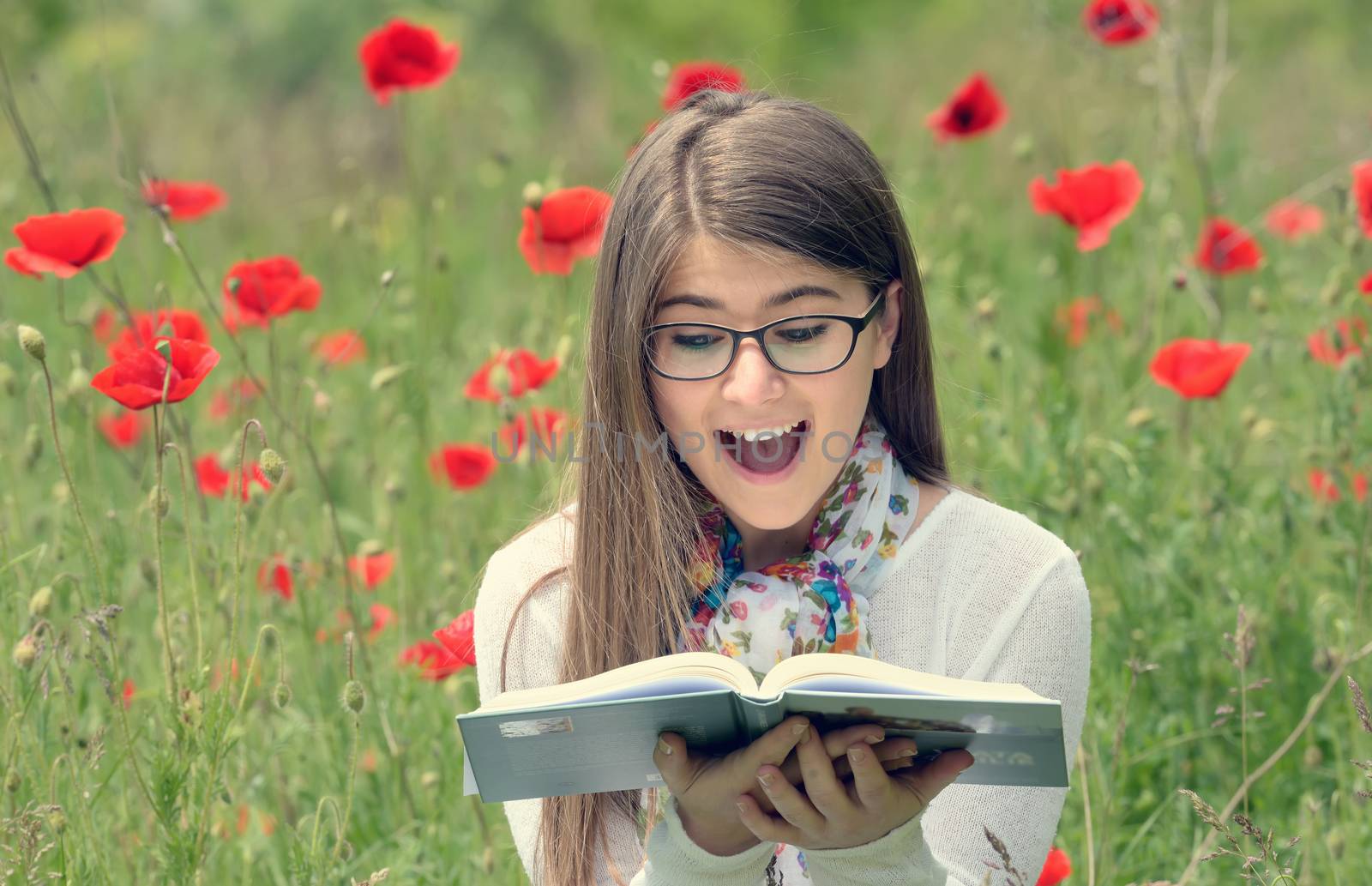 Teenage girl read a book in poppy field
