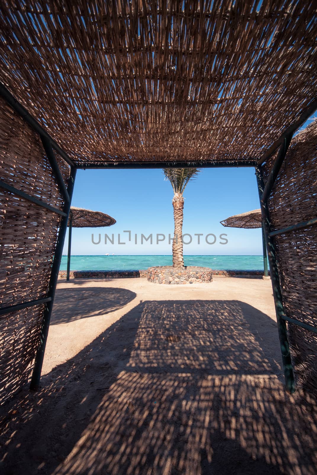 wicker sunshade shelter hovel on the beach in ocean sea resort. Vacation summer time by skrotov