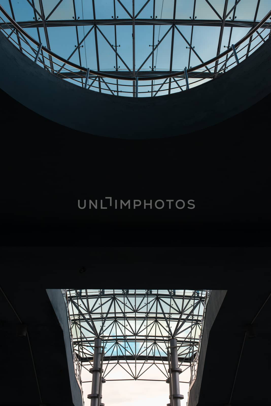 Bottom view of modern glass roof in business district in evening light at sunset with copyspace.