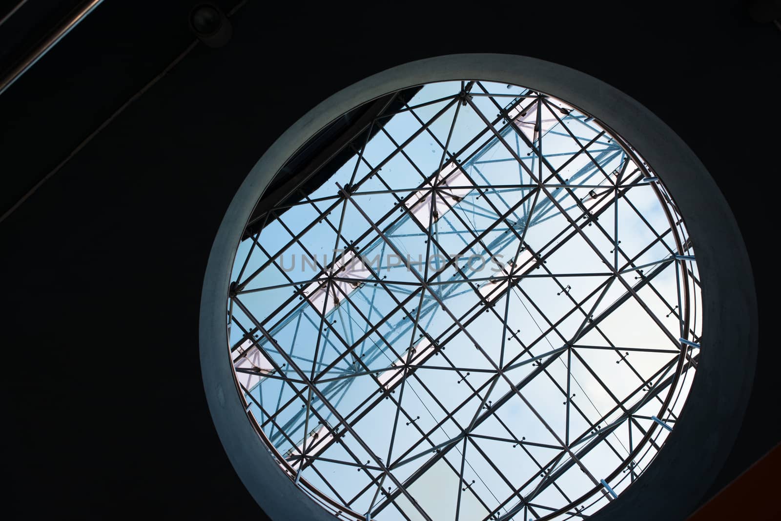 Bottom view of modern glass roof trough sircle hole in business district in evening light at sunset with copyspace by skrotov