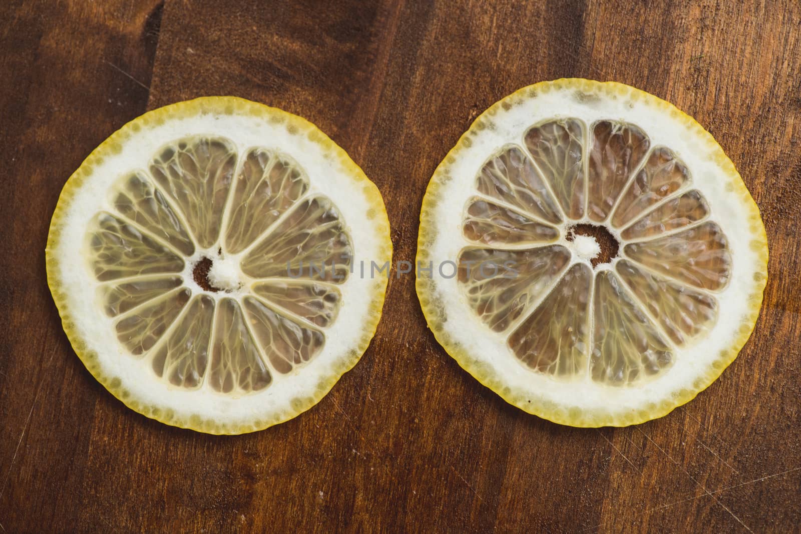 two thin slices Fresh Lemon on Wood Table Background, Rustic Style. by skrotov