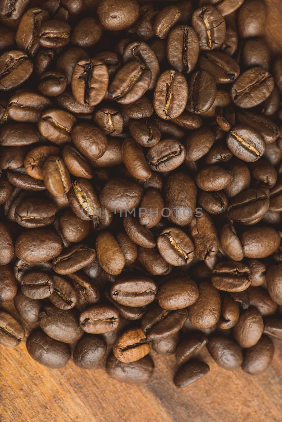 Brown coffee beans, closeup of macro coffee beans for background and texture. On brown wooden board