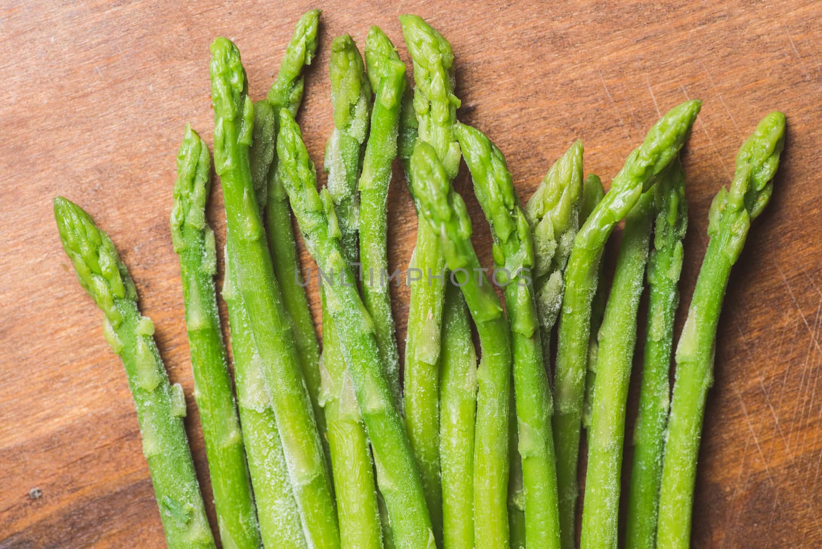 Frozen sticks of asparagus on rustic wood background. horizontal view. by skrotov