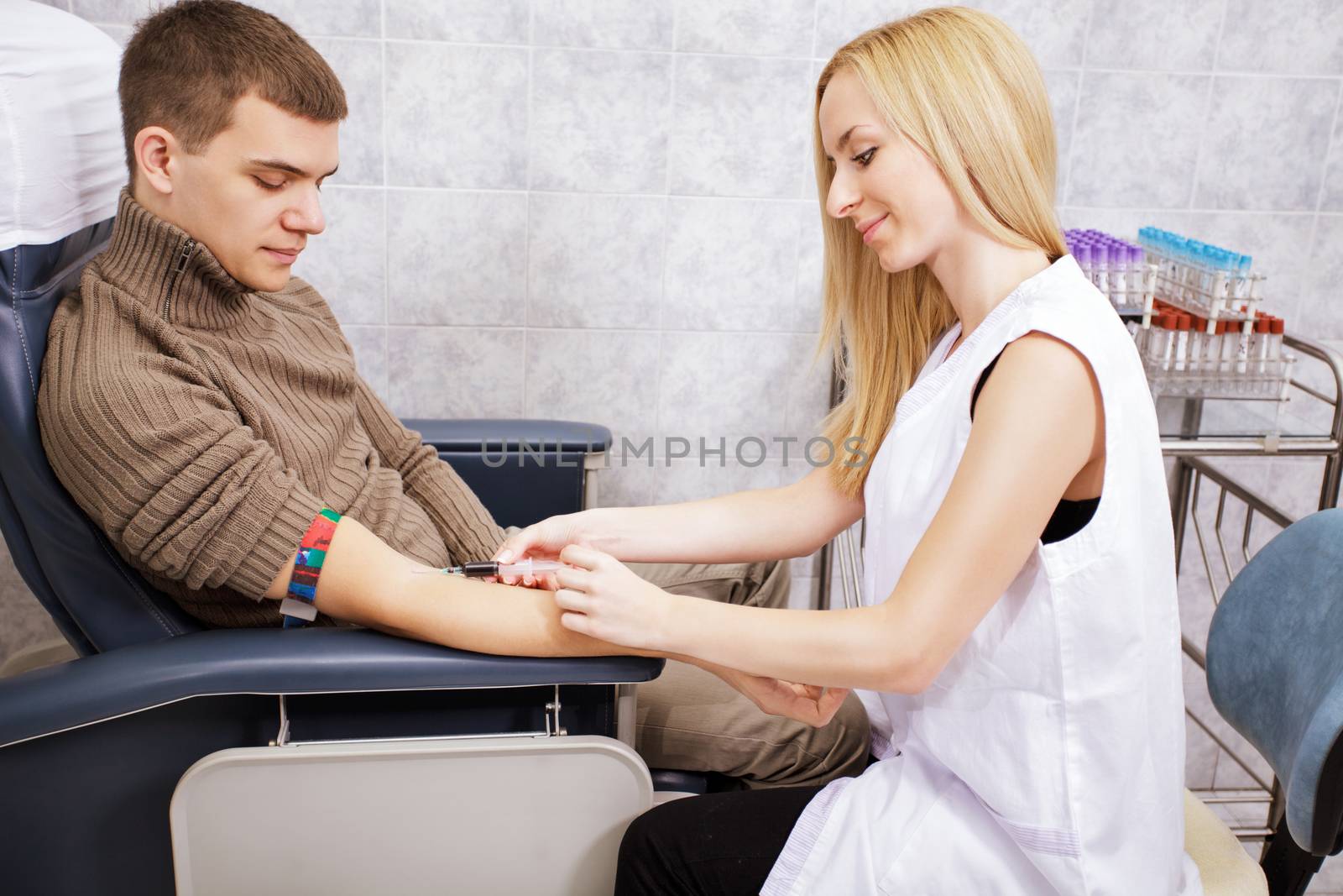 Young nurse doing procedure of a blood capture from a vein 