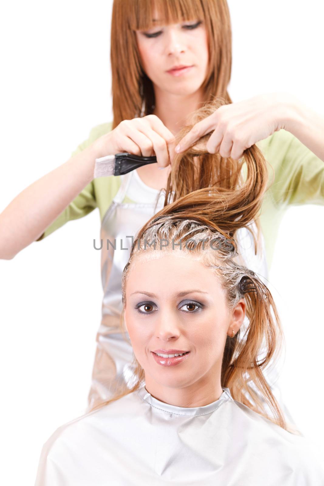 Young beautiful hairdresser coloring hair with hair color