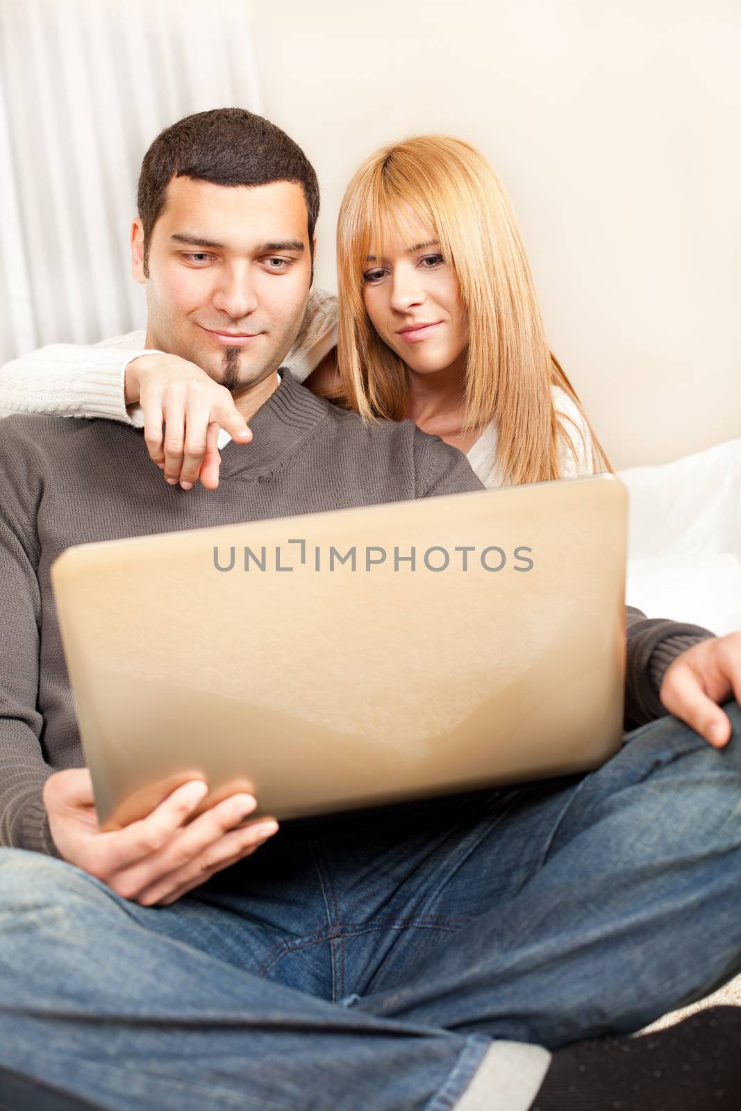 Happy young couple sitting at living room, and browsing internet