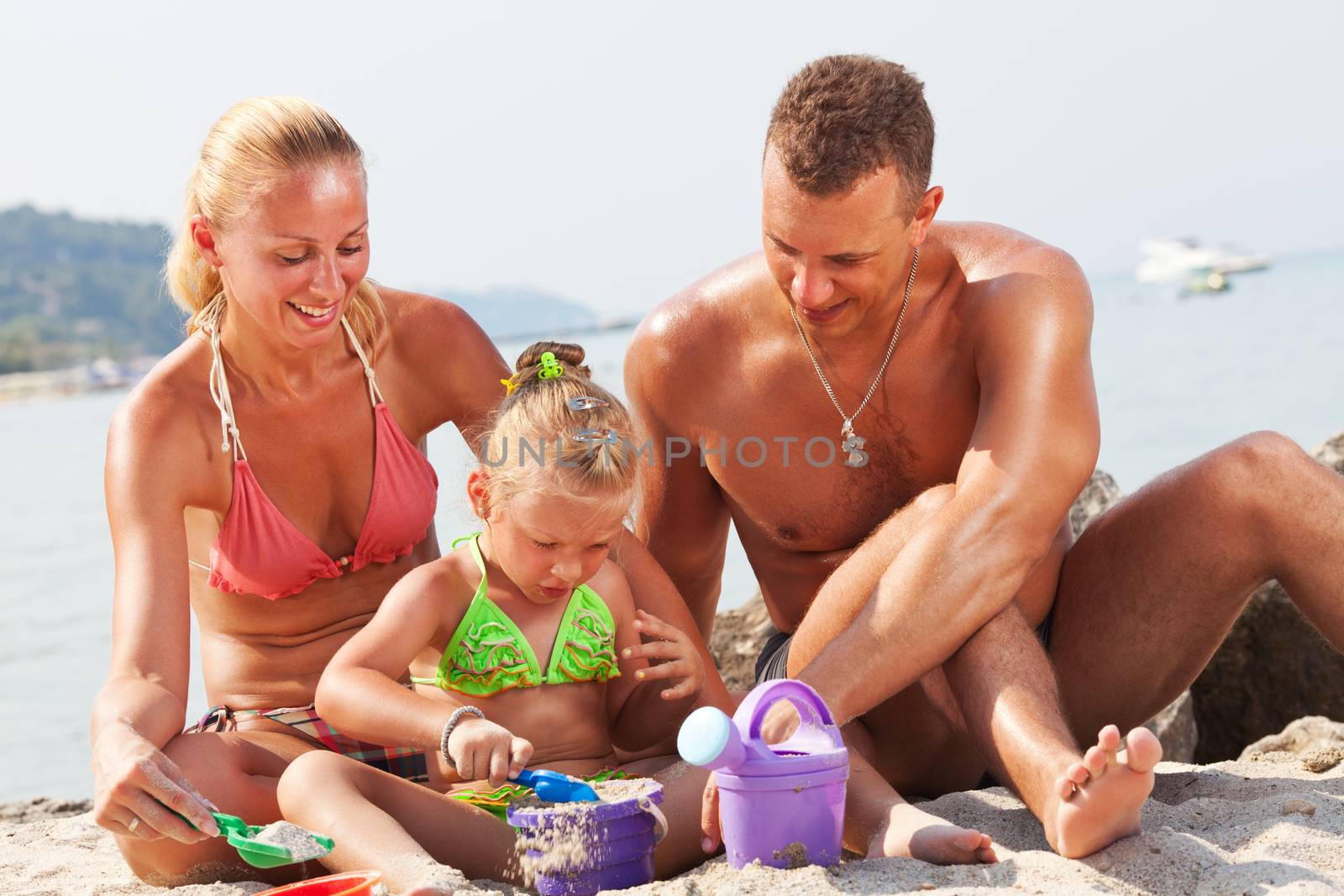 Happy family playing on the beach with bucket and spade