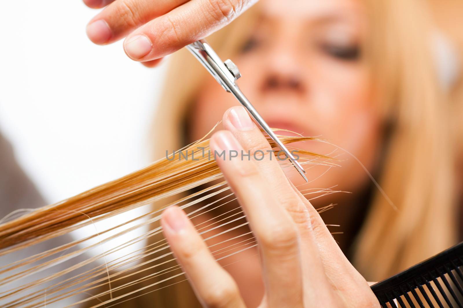 Hairdresser cut hair of a blonde woman / close-up
