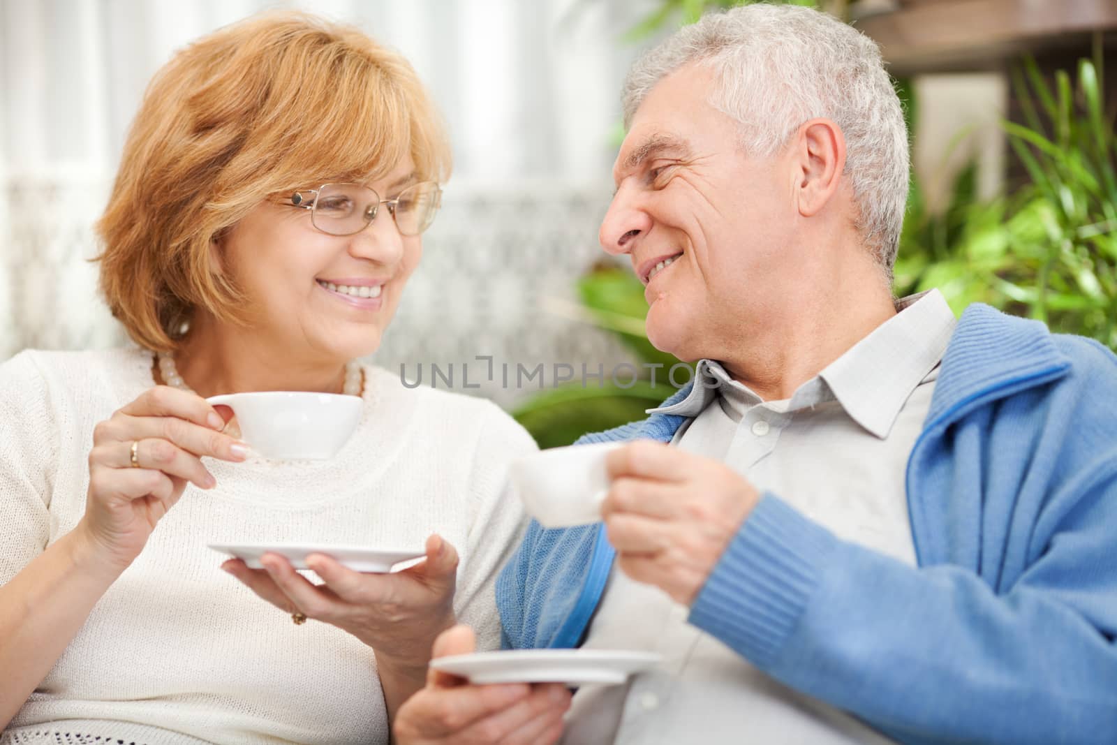 Happy senior couple drinking coffee at home