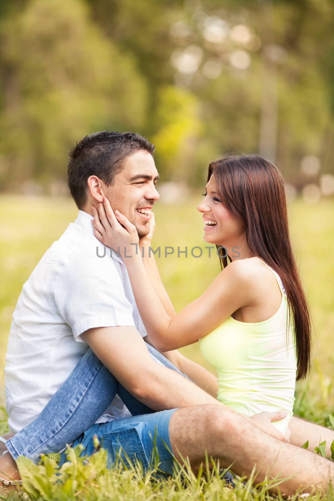 Happy young man and beautiful girl sitting in the park
