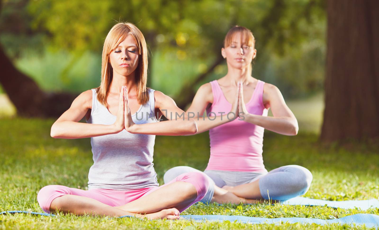 Two beautiful women meditating in the park