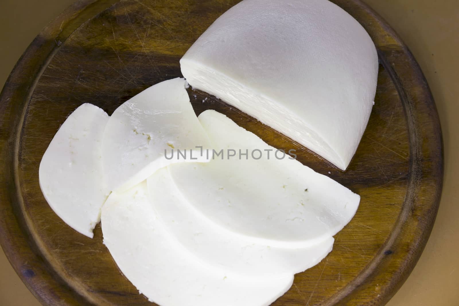 fresh cheese sliced on a wooden Dostochka very soft focus by KoliadzynskaIryna